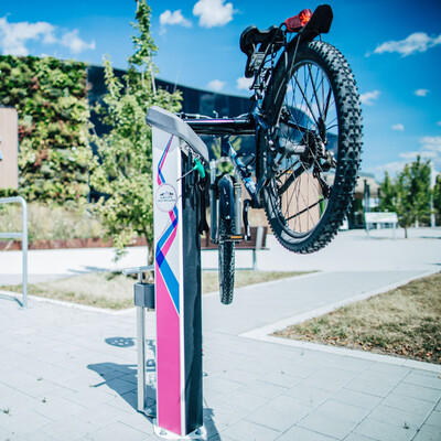 Fahrradparkplatz mit RadServicePoint, an dem ein Fahrrad aufgeh&auml;ngt ist.