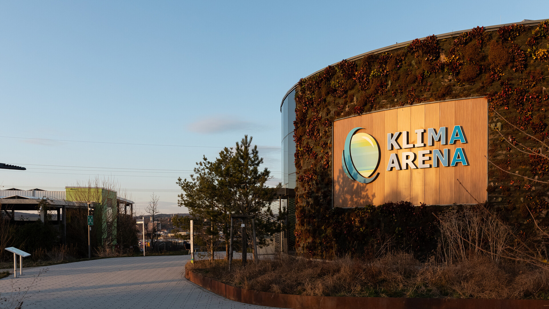 Blick auf die begr&uuml;nte Au&szlig;enfassade der KLIMA ARENA mit Logo-Wand.