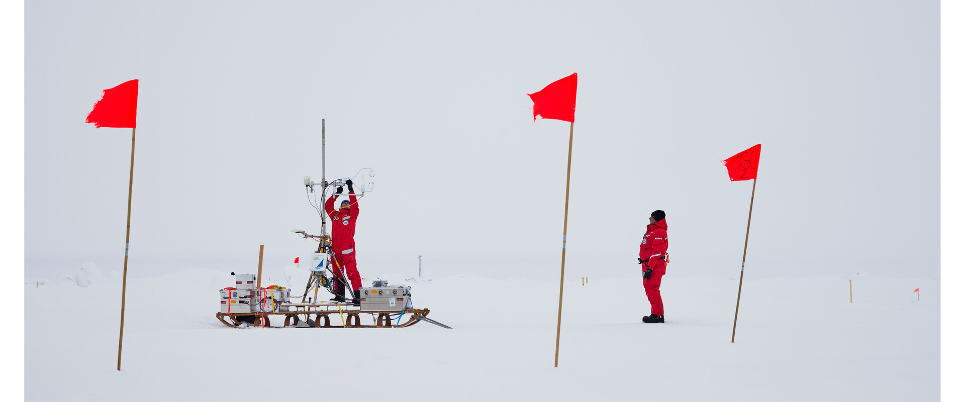 Wissenschaftler bereiten eine Bohrung in einem abgesteckten Feld auf dem Eis vor.
